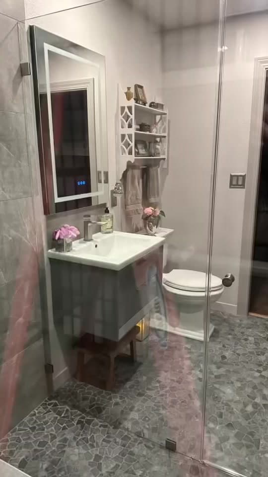 Floating bathroom vanity with an LED mirror and a glass shower enclosure.
