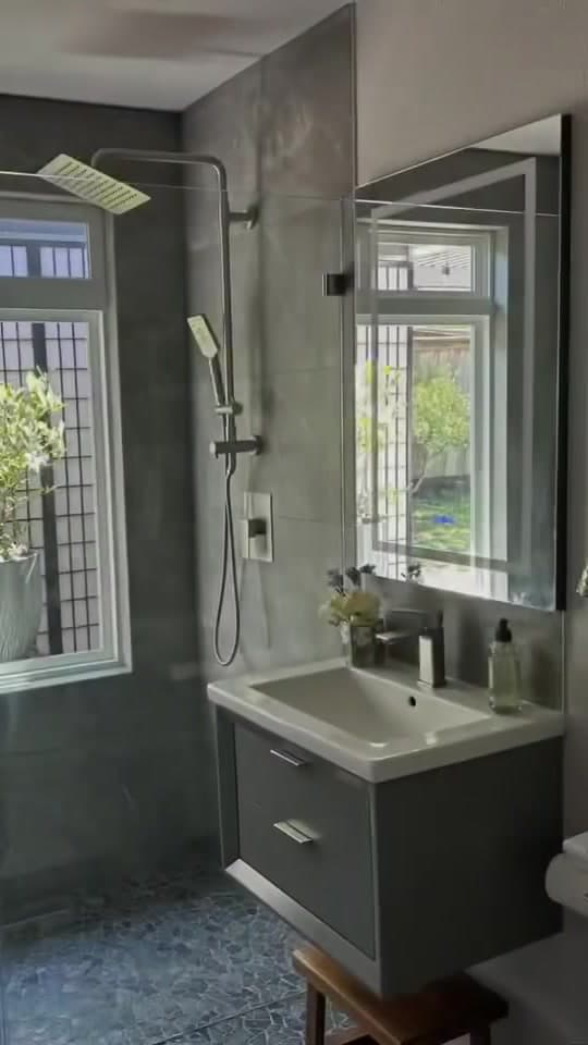 Bathroom with natural light, a floating vanity, and a rainfall shower.